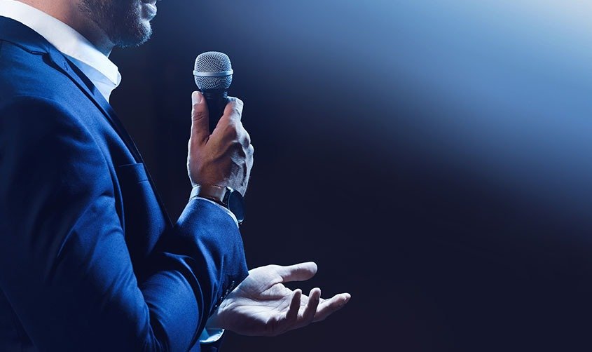 motivational speaker with microphone performing on stage, closeu